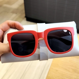 Détail de lunettes de soleil carrées rouges pour enfants avec étui en cuir blanc