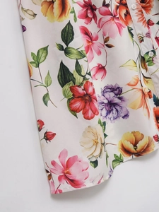 Détail d'une robe midi en popeline fleurie montrant des boutons blancs et l'ourlet