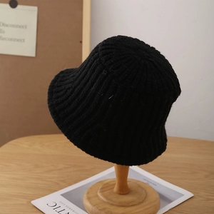 Chic black knitted bucket hat for women with ribbed texture on a wooden stand