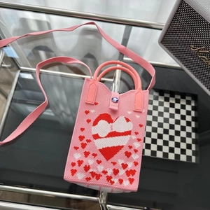 Détail du mini sac à bandoulière rose en tricot avec motifs cœurs et ornement gemme