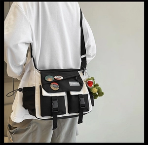 Detail of crossbody bag featuring black and white paneling with a green dinosaur charm