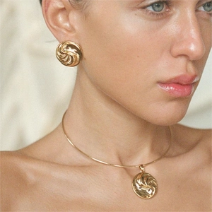 Elegant 18k gold vortex earrings and necklace set worn by a model in soft lighting