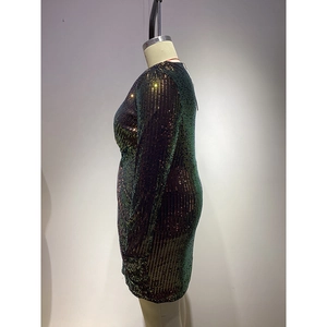 Dettaglio dell'abito con paillettes verde scuro a maniche lunghe e texture increspata