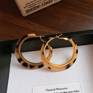 Detailed shot of leopard print hoop earrings with elegant gold trim on dark wood