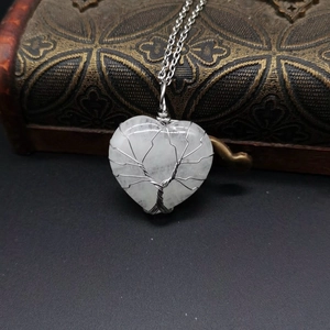 Macro detail of silver wire-wrapped tree of life design on heart-shaped crystal pendant