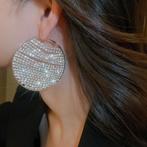 Close-up of oversized silver hoop earrings with shimmering rhinestones on a female model