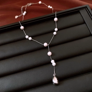 Detailed view of silver Y-shape necklace with white beads and dark teardrop pendant