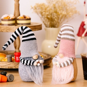 Striped Christmas faceless gnome plush dolls with knitted hats on a warm wooden tray