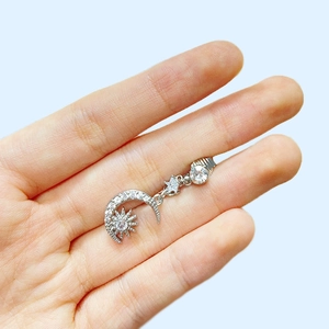 Silver crescent moon and star belly ring with clear crystals shown in hand