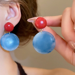 Detailed view of red and blue marble resin drop earrings featuring a round geometric design