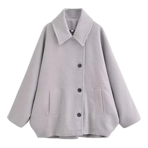 Close-up of a grey wool coat with lapel collar, single-breasted buttons, and flap pockets