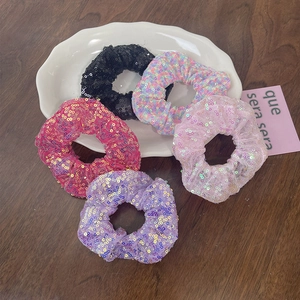 Detail of 5-piece sparkly sequined oversized hair scrunchies on a white wavy plate