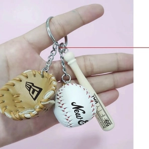 Detailed view of mini baseball glove, bat, and ball keychain on pink background