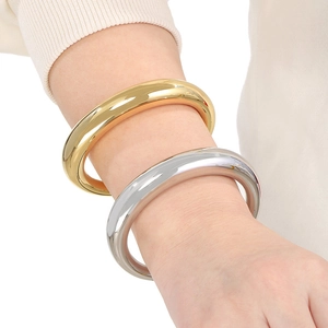 Gros plan de bracelets joncs en C évidés minimalistes en or et argent sur un poignet