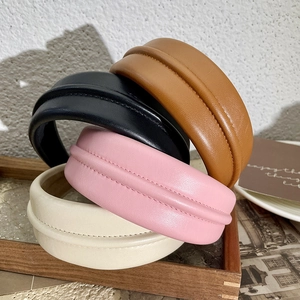 Vue détaillée de serre-têtes rembourrés en similicuir empilés en marron, noir, rose et beige