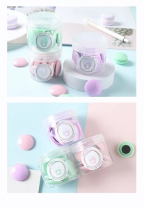 Gros plan d'aimants en forme de macarons rose, violet et vert dans un bocal rond transparent