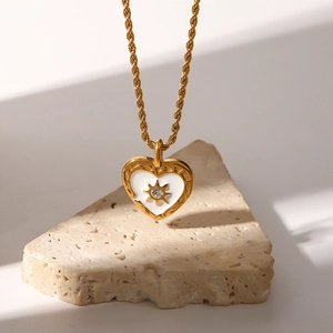 Detailed close-up of golden heart pendant with sunburst pattern and clear zircon