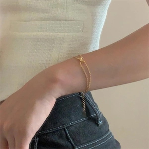 Detail of 925 sterling silver double-layer golden twist bracelet with a butterfly charm