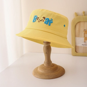 Détail du chapeau bob jaune pour enfant avec broderie Bear sur un support en bois