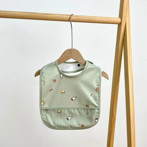 Close-up of waterproof baby bib in light green with astronaut and rocket pattern