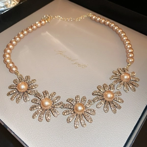 Detailed macro view of daisy flower charms with sparkling rhinestones on pearl necklace