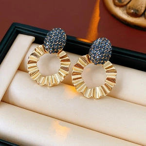 Detail of gold hoop earrings with blue rhinestones in a luxury beige jewelry box
