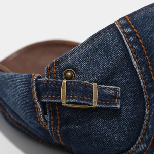 Detailansicht der gewaschenen Jeansmütze mit orangefarbenen Nähten und Messingschnalle