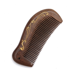 Macro detail of sandalwood massage comb featuring golden inlay patterns on wood