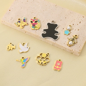 Detailed shot of nine enamel animal charms with pearls on beige stone and gold silk fabric