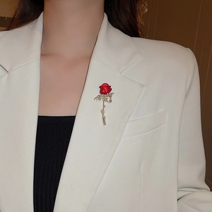 Detail of red rose brooch with gold diamond stem worn on a white suit lapel
