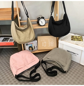 Close-up of four nylon crescent crossbody bags in beige, black, pink, and grey-green colors