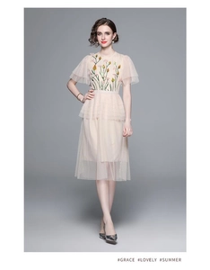 Detail of floral embroidery and layered polka dot tulle on a light pink dress