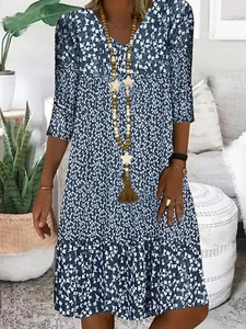 Detail of V-neck neckline on a dark blue floral summer dress with a wooden necklace
