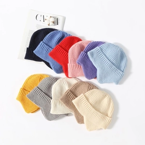 Detailed flat lay of knit earflap beanies in multiple colors with wool texture