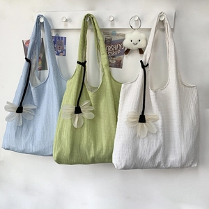 Macro shot of colorful textured pleated tote bags with mesh flower pendants and long handles