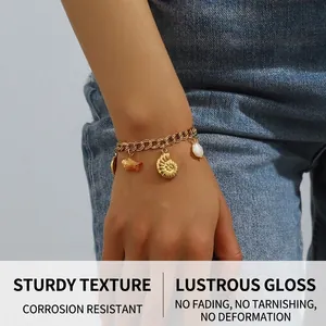 Détail d'un bracelet chaîne doré avec breloques marines porté sur fond en jean bleu