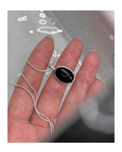 Macro detail of silver oval black onyx pendant with sleek snake chain and water drops