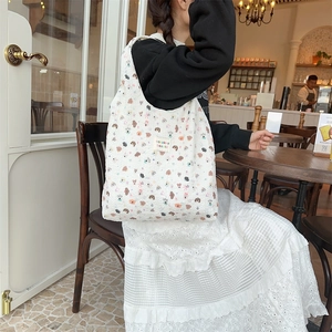Detail of white quilted tote bag with colorful animal prints and brand woven label