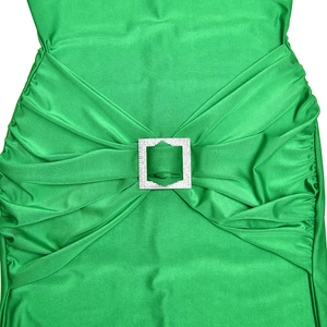 Detailed macro view of the sparkling rhinestone buckle and elegant green pleated fabric