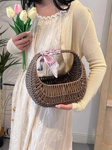 Brown woven rattan hand basket bag featuring a pink silk scarf on handle for women