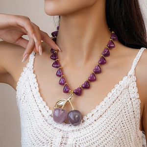 Close-up of a purple heart beaded necklace featuring a large glittery cherry pendant