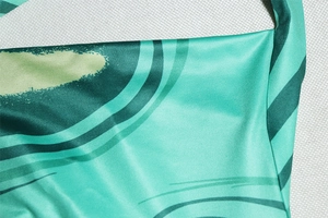Detail of green printed fabric with wavy line patterns and smooth textured polyester finish