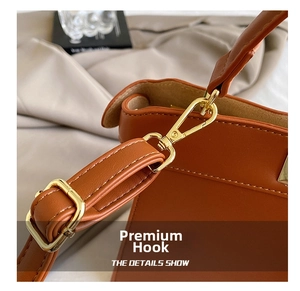 Detail of caramel brown leather strap with polished gold hardware hooks and buckle