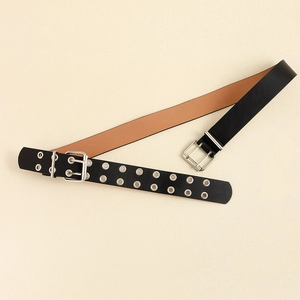 Detail of Y2K punk style black studded leather belt with silver double buckle on beige texture
