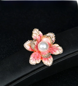 Detailed macro view of pink enamel flower brooch with rhinestones and center pearl