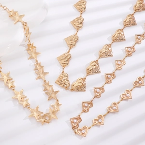 Detail of three gold-plated chain belts featuring star, pearl heart, and textured heart designs