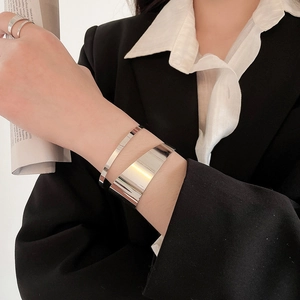 Detail of minimalist silver bangles and rings styled with a professional suit