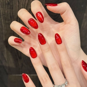 Short oval cat-eye press-on nails in deep ruby red wine color with gold glitter shimmer