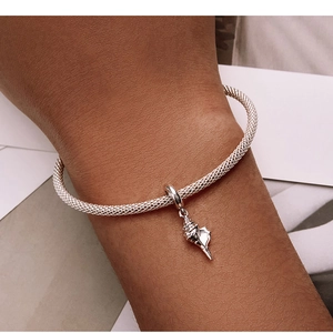 Détail d'un bracelet en maille argentée avec un pendentif coquillage texturé