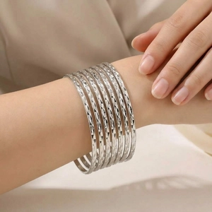 Detail shot of multi-layered silver steel bangles with diamond-cut patterned texture